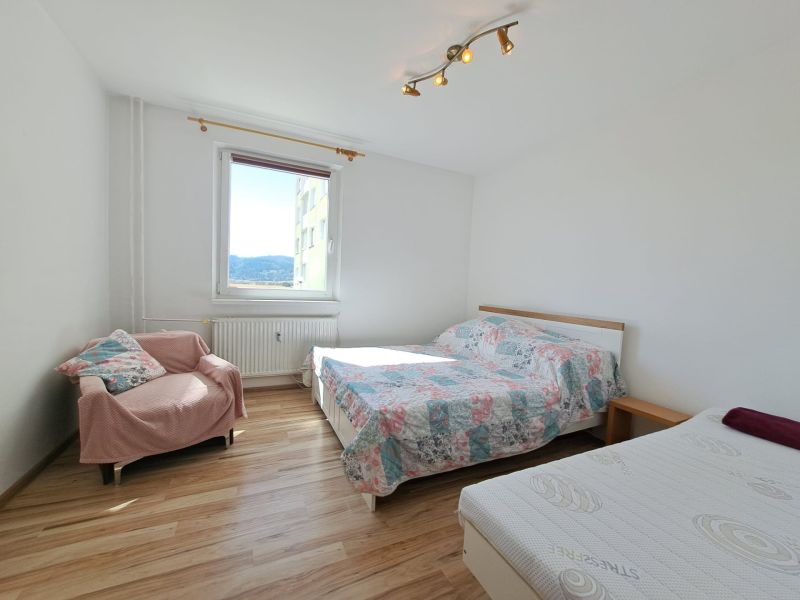 A bright bedroom in a three-room apartment with a window and a wooden decor floor.