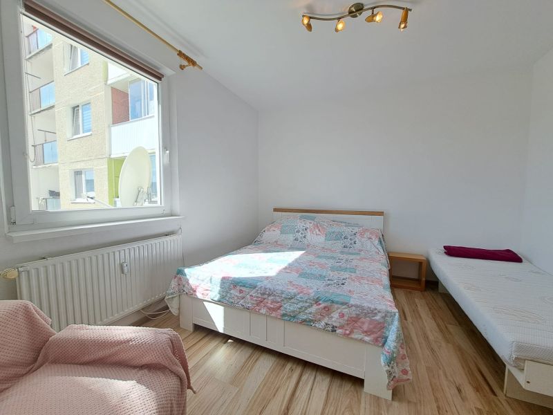 A bright bedroom in a three-room apartment with beds and wood-decor flooring.