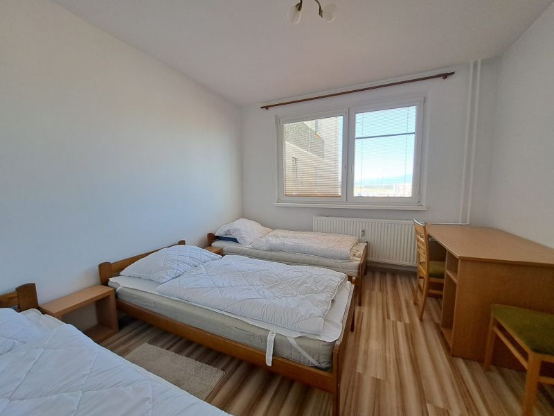 A bedroom with three beds and a table in a 3-room apartment, floor with wood decor.