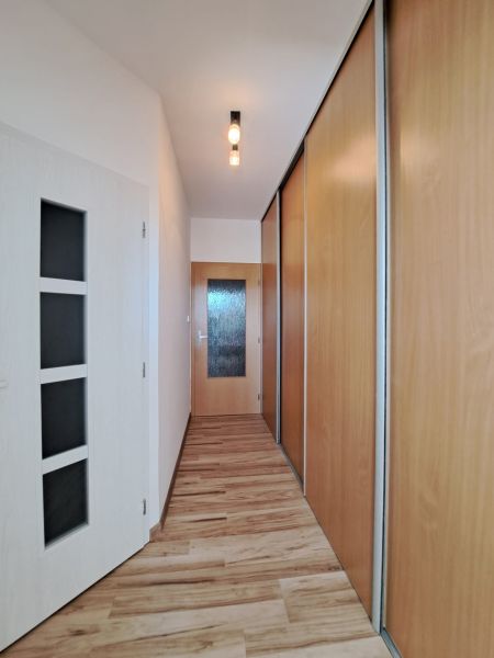 A hallway in a 3-room apartment with a wooden decor floor and built-in wardrobes.