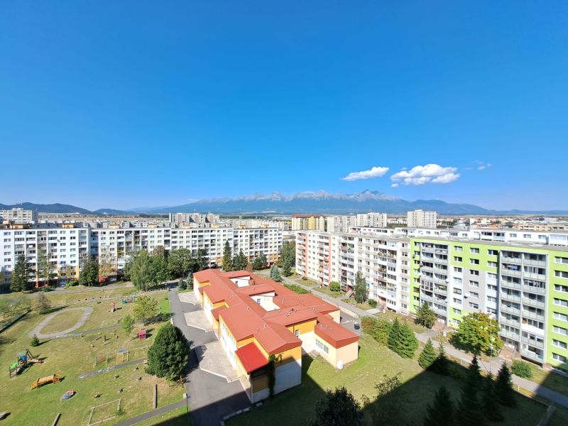 View of the housing estate with a playground, buildings, and mountains in the background in Poprad on Jesenná Street.