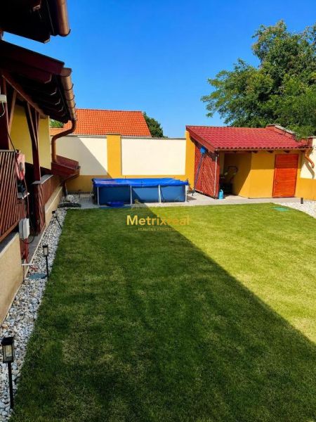 The garden of a family house in Darnózseli with a lawn and a swimming pool, surrounded by a fence.