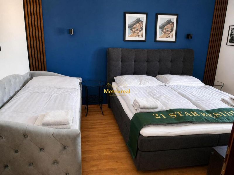Bedroom with a double bed, blue wall, and wood-patterned floor.