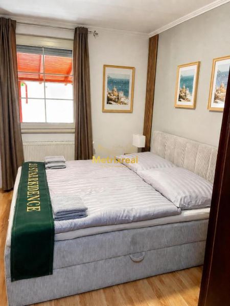 Bright bedroom in a family house with a large bed and wood-patterned flooring.