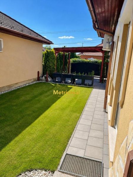 The garden of a family house in Darnózseli with a green lawn and a paved pathway.