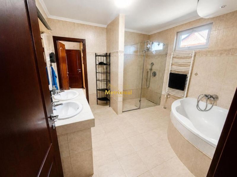 A bathroom in a family house with a double sink, shower, and bathtub.