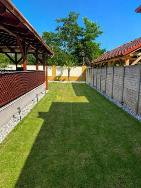 The garden of a family house in Darnózseli with a lawn, pergola, and surroundings of trees.