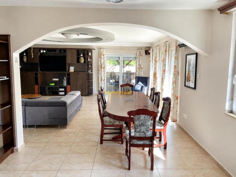 Dining table and sofa in a bright interior of a family house with tiles.