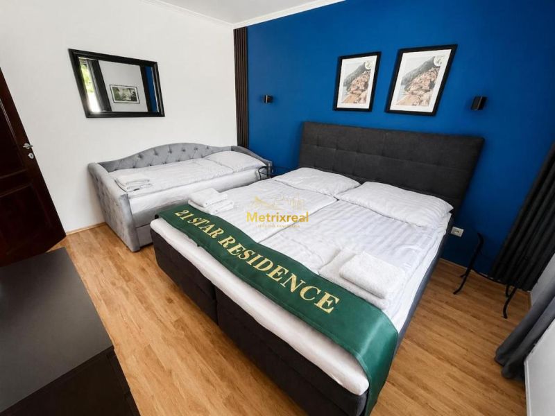 A bedroom in a family house with a wooden decor floor and a dark blue wall.