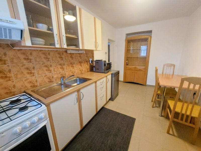 A kitchen in a 2-room apartment with a dining table, ceramic tiles, and a kitchen unit.