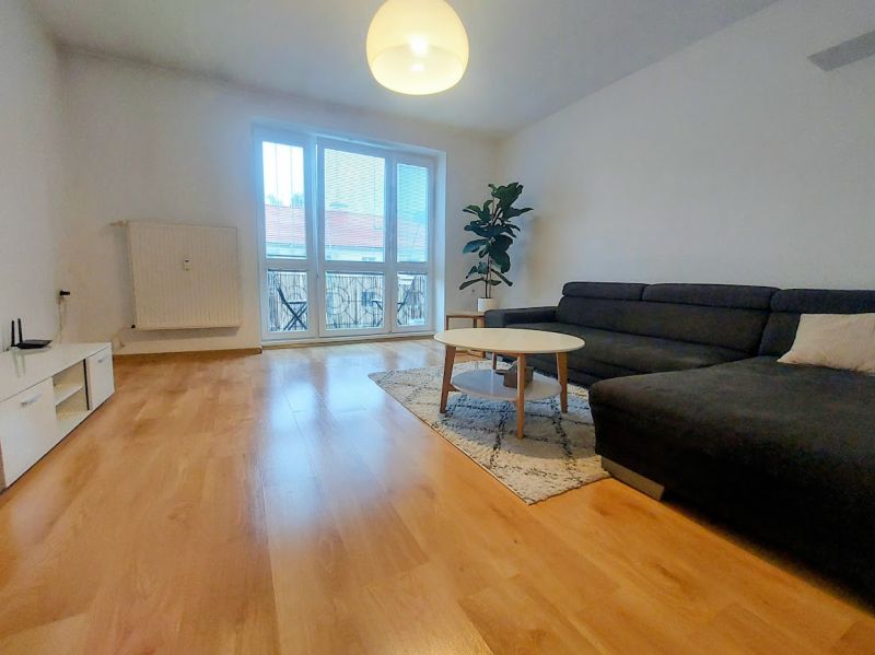 Living room with wood-patterned flooring, a sofa, and a coffee table in a two-room apartment.