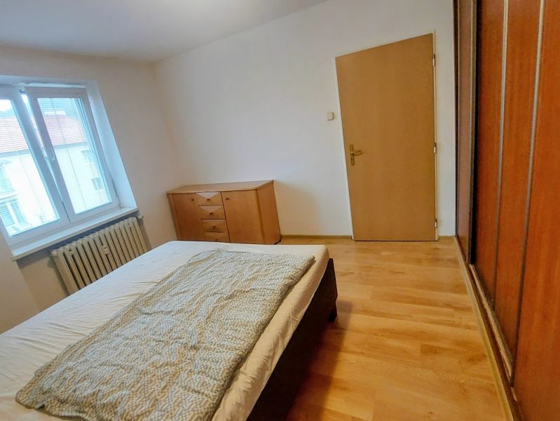 Bedroom with a bed, dresser, and wooden decor flooring in a two-room apartment.