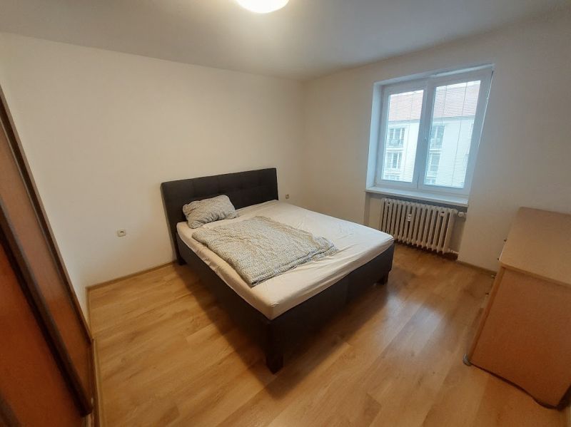 Bedroom with a bed and wooden decor flooring in a two-room apartment.