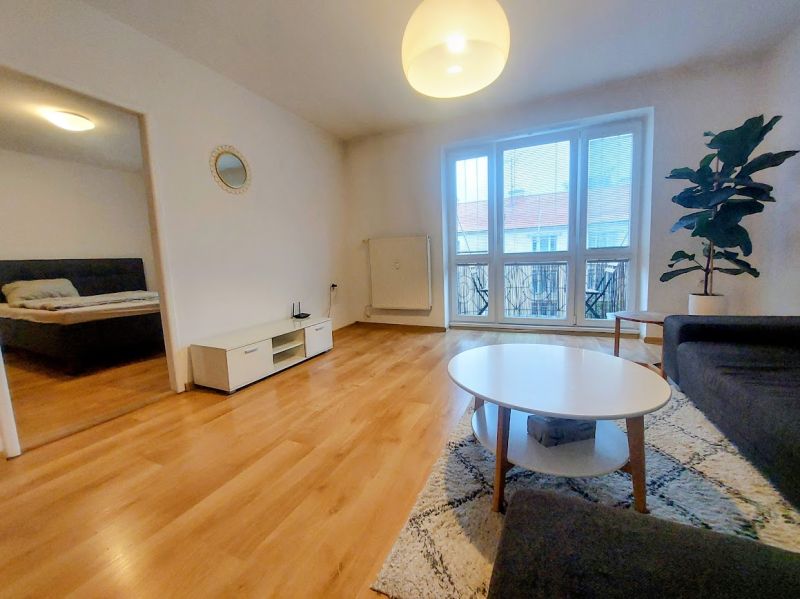 Living room of a two-room apartment with a wooden decor floor and spacious windows.