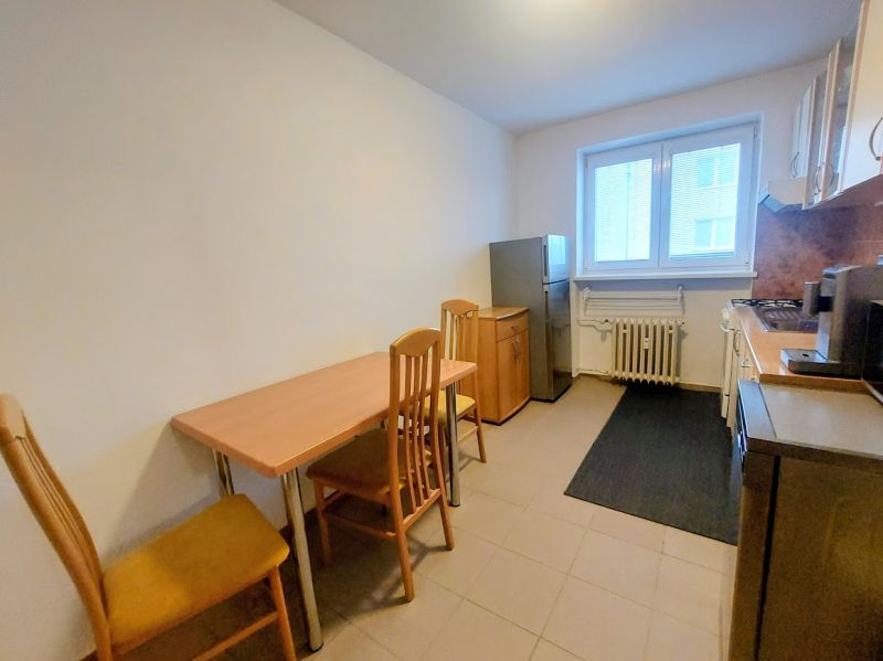 A kitchen in a 2-room apartment with a dining table and chairs made of wood.