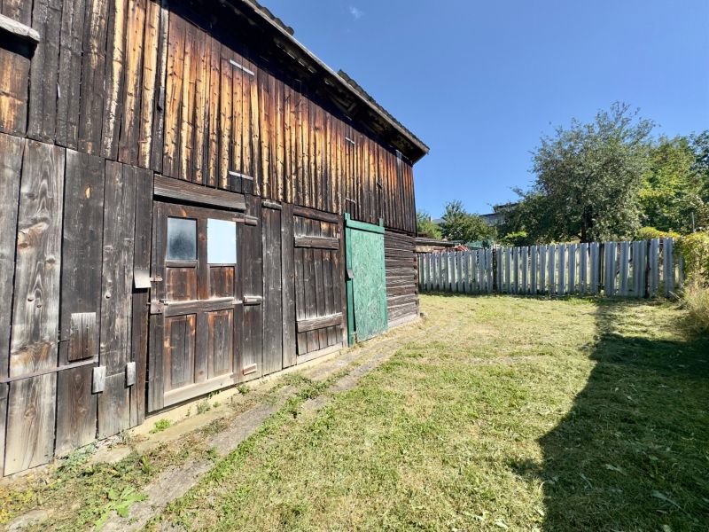 Wooden part of a family house in Lipany, fenced garden and woodshed.
