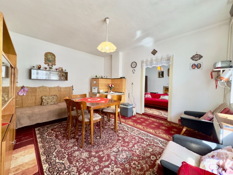 A dining room with a patterned carpet and wooden furniture in a family house.