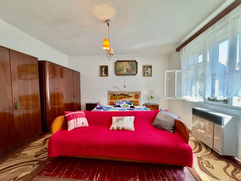 A bedroom with carpets, a red sofa, and retro furniture in a family house.