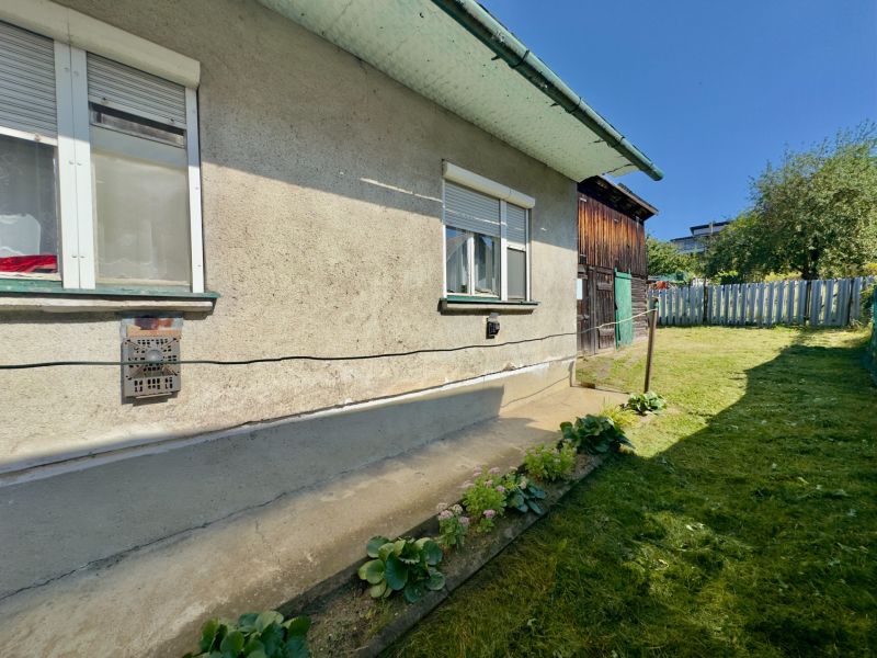 A family house in Lipany with a garden, flower bed, grassy yard, sunny day.