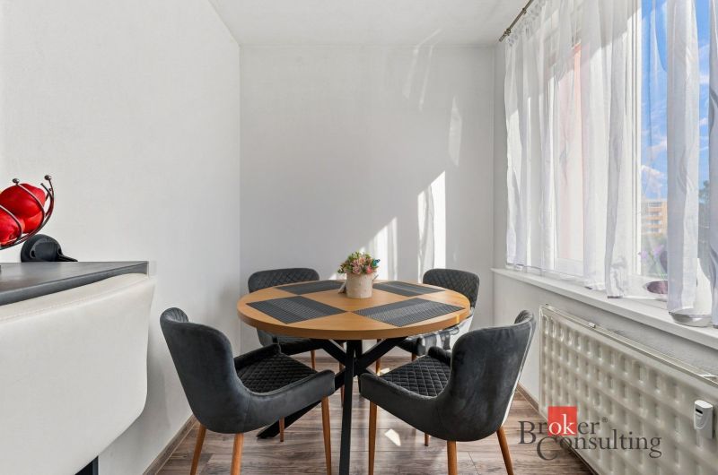 A kitchen in a 2-room apartment with a counter, appliances, and a wooden decor floor.