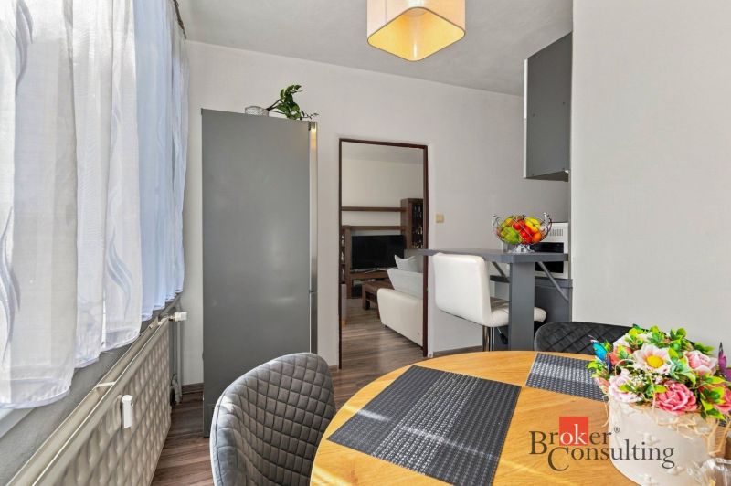 Dining area in a 2-room apartment with a table and chairs, flowers on the table.