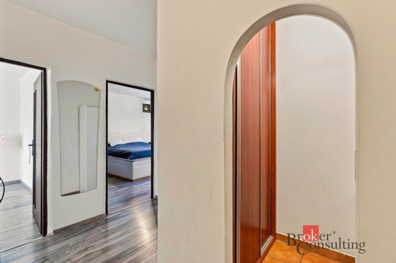 A bright bedroom with a bed, a television, and a wooden decor floor in a two-room apartment.