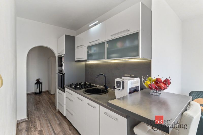 A bright living room in a 2-room apartment with furniture and a TV, floor with a wooden decor.