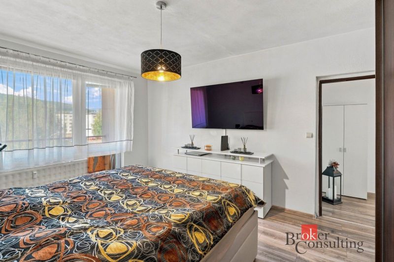 A bedroom with a bed, wardrobe, and wooden decor flooring in a two-room apartment.