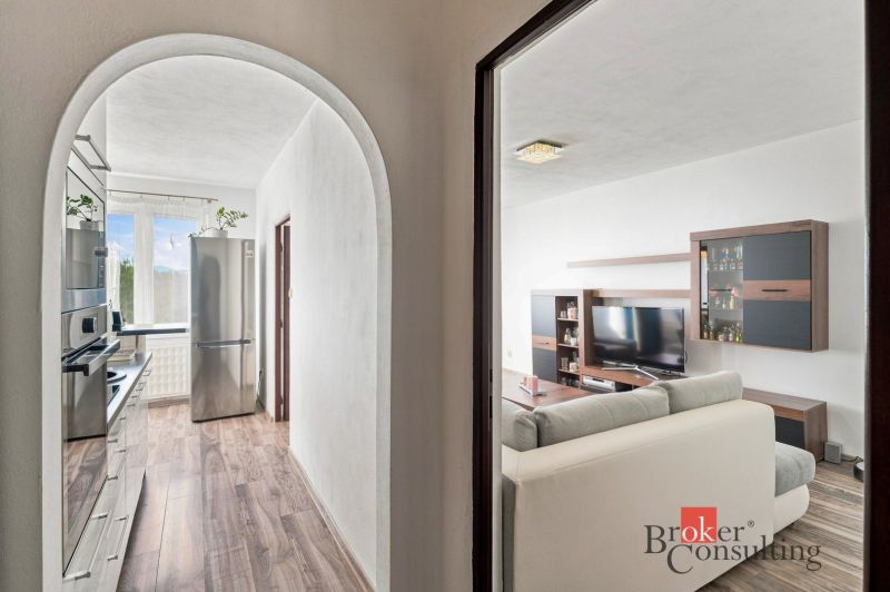 A hallway with a mirror and a view into the bedroom, wooden decor flooring in a 2-room apartment.