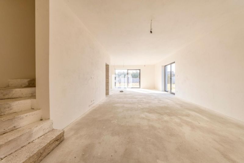 Interior of a family house with an unfinished floor and large windows, stairs on the side.
