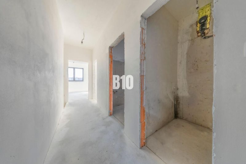 A hallway of a family house with a view of the window, unfinished walls and floors.