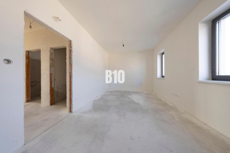 Empty room in a family house with white walls and a concrete floor.
