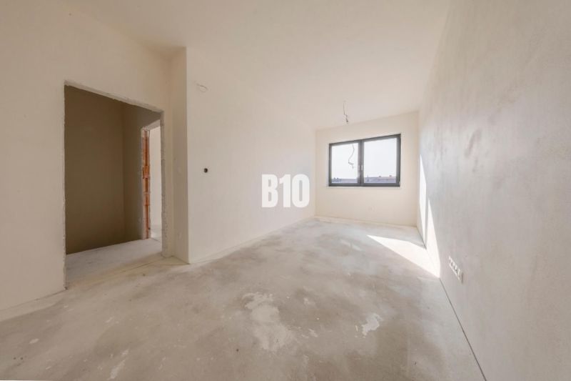 A bright room in a family house with a concrete floor and a large window.
