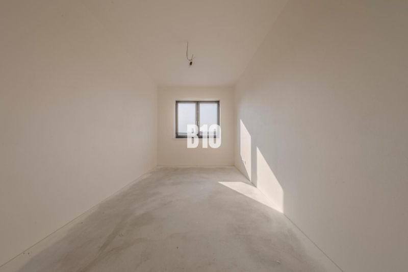 Empty room with a window, white walls, concrete floor surface in a family house.
