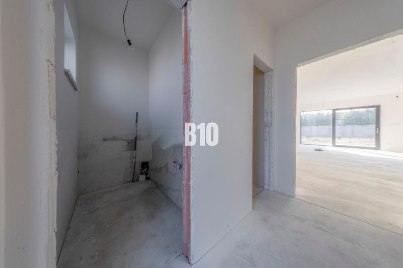 The interior of an unfinished family house with open spaces and large windows.