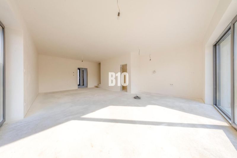 A spacious interior of a family house with large windows and white walls.