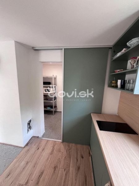 A kitchen in a cottage with a wooden decor floor and sliding doors.