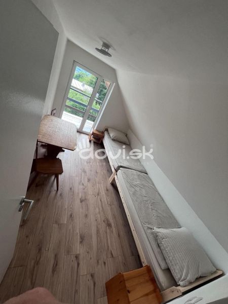 A room in a cottage with a wooden decor floor and a view of greenery.