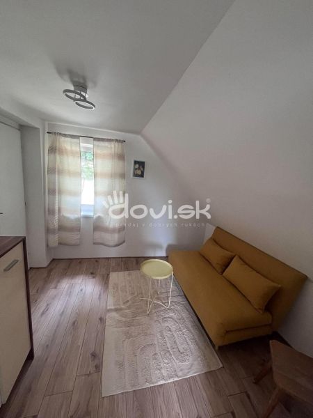 Living space in a cottage with a yellow sofa and wood-patterned flooring.