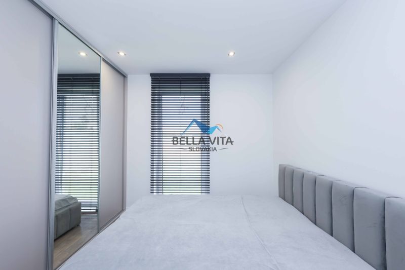 A bedroom in a family house with a bed, a mirrored wardrobe, and blinds on the window.