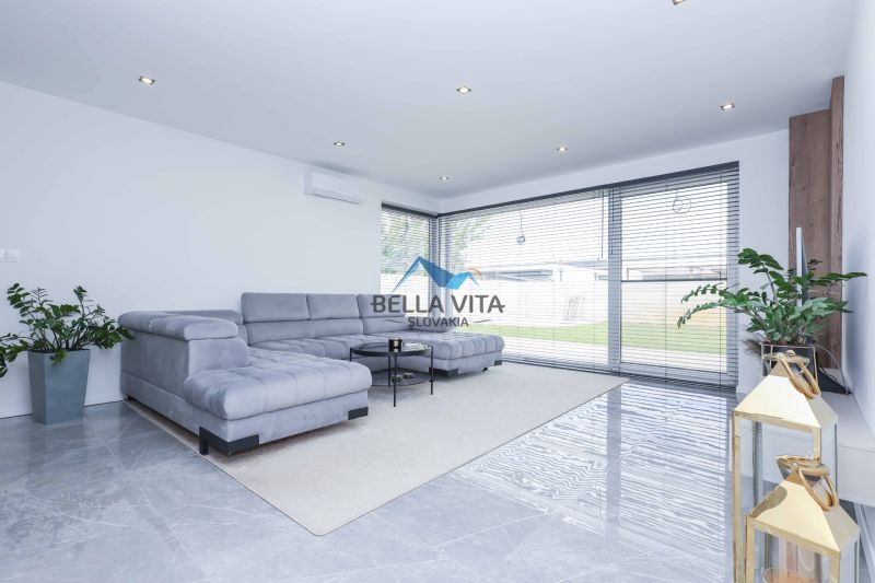 Living room with a spacious sofa and large windows in a family house.