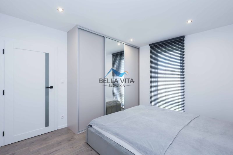 A bedroom in a family house with a bed, a wardrobe, and a wooden decor floor.