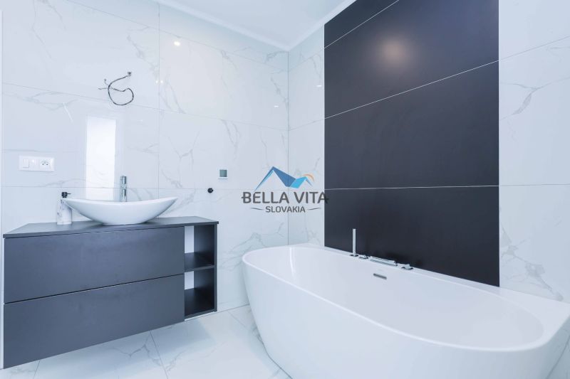 Bathroom in a family house with a bathtub, sink, and white tiles.