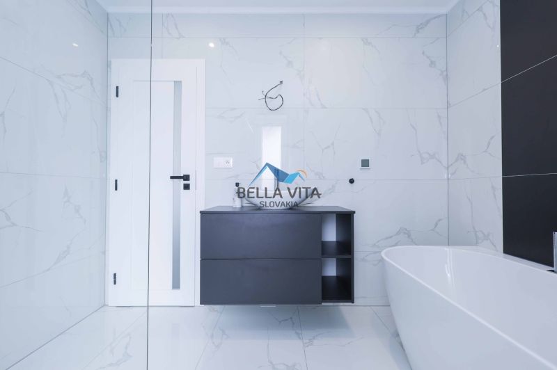 A bathroom in a family house with white tiles and a dark washbasin counter.