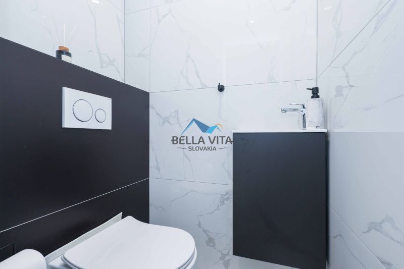 A bathroom in a family house with a toilet and a sink on a marble tile.