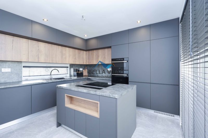 A kitchen in a family house with a kitchen island and gray cabinets.