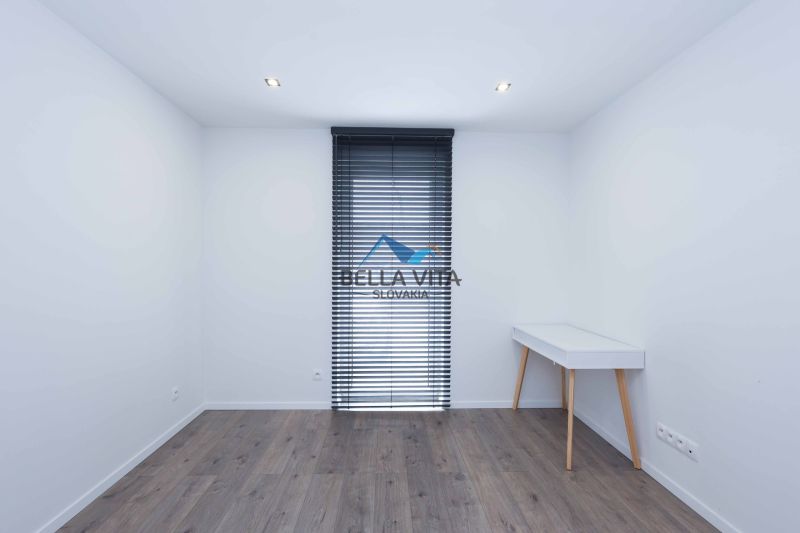 Room in a family house with a wooden decor floor and a table next to the window.