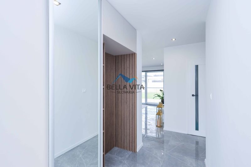 Interior of a family house with tiles, wooden panel, plant, and glass doors in the background.