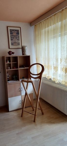 Interior of a family house with a wooden decor floor, a shelf, and a high chair.