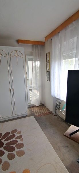 A room in a family house with white furniture, a television, and a carpet with a flower pattern.